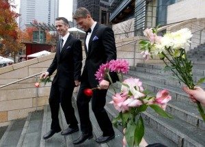 Dan Savage (kiri) dan Terry Miller meninggalkan Seattle City Hall, setelah diresmikan sebagai pasangan gay pertama yang menikah./* *AP Photo/Elaine Thompson