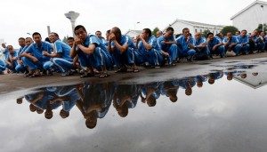 Sejumlah pecandu narkoba berjongkok saat mereka menunggu makanan mereka di pusat rehabilitasi Shiliping , Tiongkok, 18 Juni 2014. REUTERS/William Hong