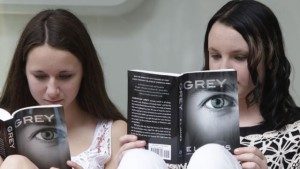 Olivia Jackson, 15 tahun, kiri, dan Julia Cebula, 14 tahun, dari Philadelphia, membaca buku terbaru dari EL James, 'Grey,' saat mengantri untuk mendapatkan tanda tangan penulis tersebut di toko buku Barnes and Noble di New York.