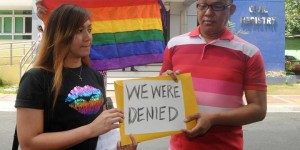 Maria Arlyn Ibanez (33) yang didampingi seorang kawannya membentangkan spanduk dan bendera warna pelangi setelah permohonanannya mendaftarkan pernikahannya dengan sang pasangan ditolak pemerintah Filipina.(foto:JAY DIRECTO/AFP)